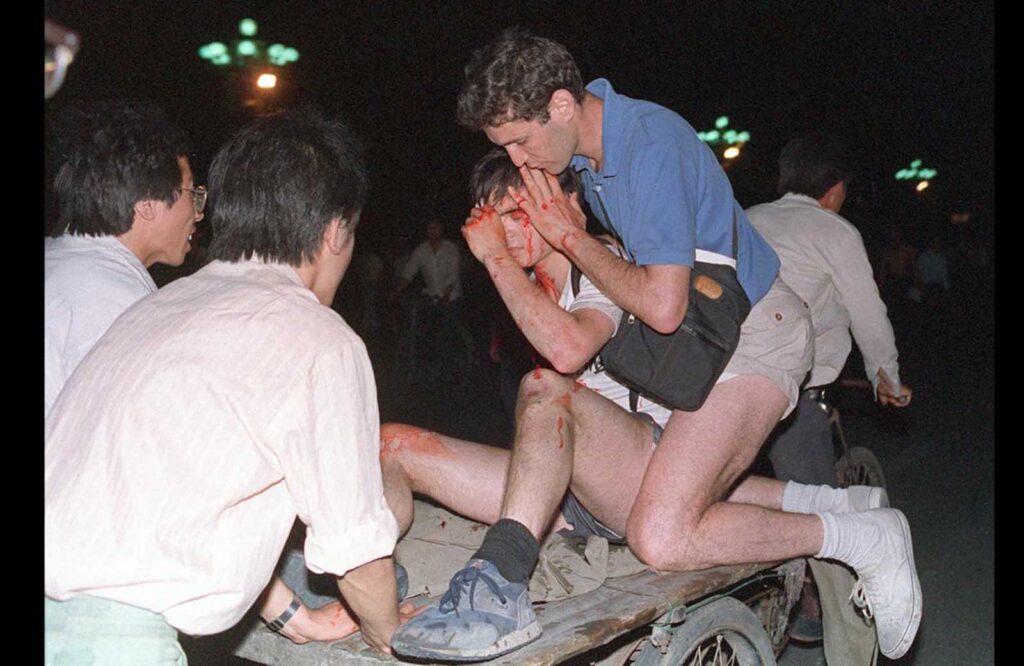 Cuidada por outros, uma jornalista estrangeira não identificada (2ª da direita) é carregada para longe do confronto entre o exército e estudantes perto da Praça da Paz Celestial, em 4 de junho de 1989.