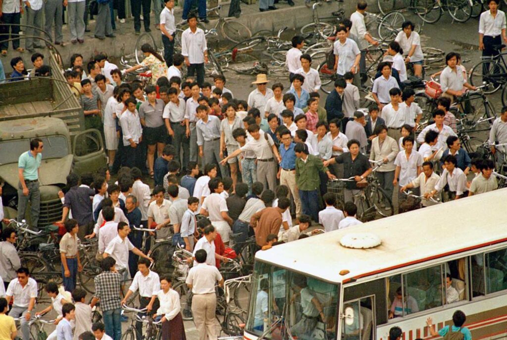 Uma multidão de chineses abre caminho para dar a um ônibus cheio de turistas estrangeiros a chance de ver o cadáver de uma vítima da primeira noite de violência enquanto as tropas do Exército de Libertação Popular disparavam na Praça da Paz Celestial para reprimir os protestos pró-democracia, na manhã de segunda-feira, 5 de junho de 1989.