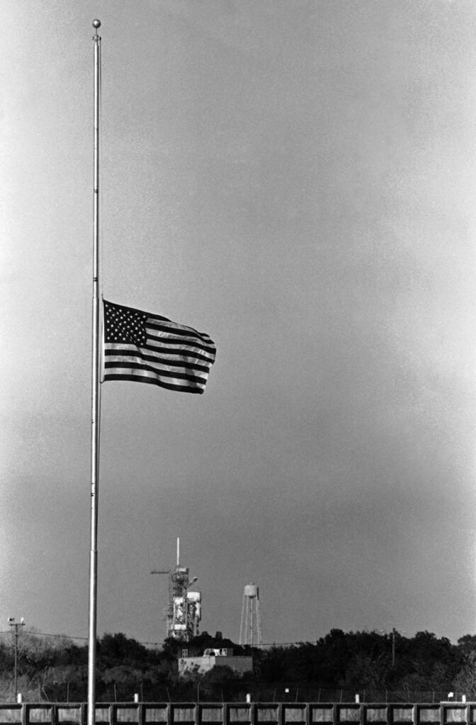 Uma bandeira tremula a meio mastro no Centro Espacial Kennedy após a explosão. (Imagem: Jim Cole / AP).