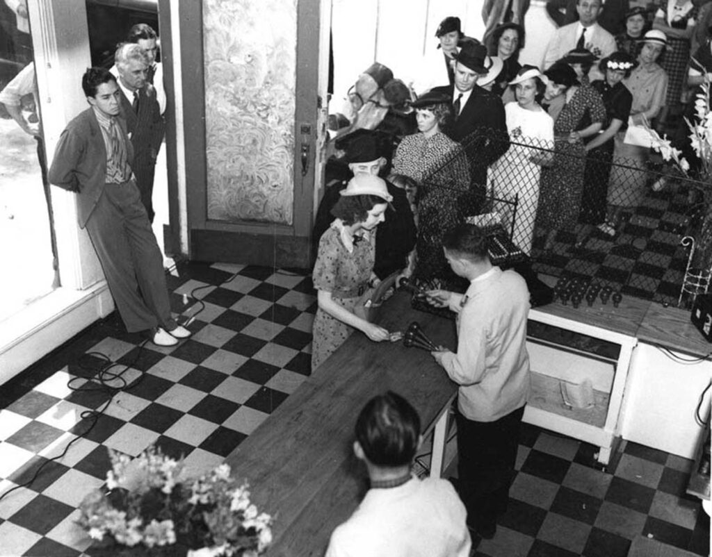 Saunders, na porta à esquerda, observa os funcionários distribuindo as chaves aos clientes.