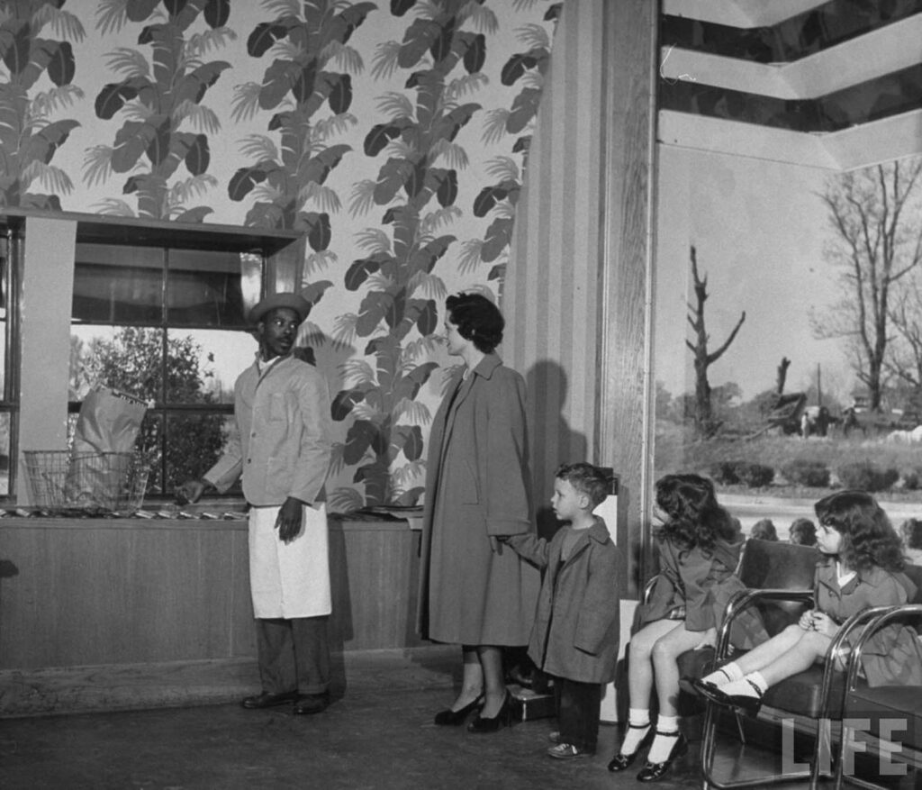 Funcionário da loja de alimentos automática Keedoozle recebendo as compras ensacadas de um cliente.