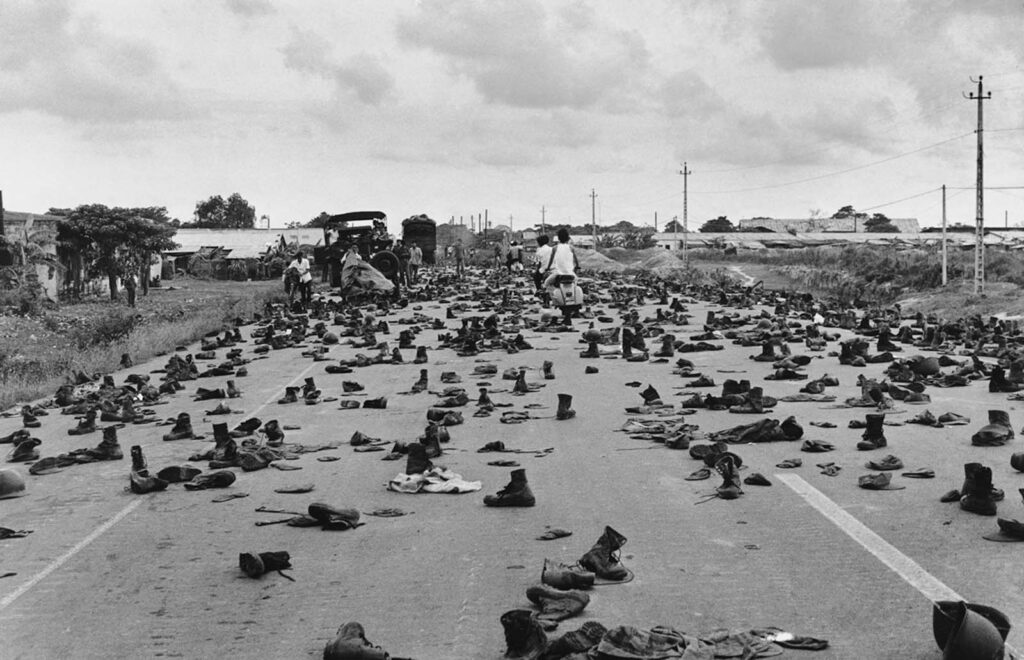 Botas de combate cobrem a rua nos arredores de Saigon, abandonadas por soldados da ARVN que tiraram seus uniformes para esconder seu status. "Nunca esquecerei os sapatos e o som alto de 'tum, tum, tum' enquanto passávamos por cima deles", relembrou o fotógrafo. "Décadas de guerra haviam terminado e finalmente tínhamos paz." 1975. (Foto de Duong Thanh).