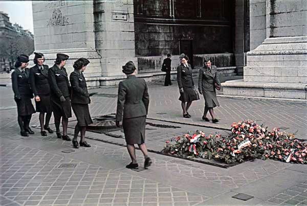 Mulheres em uniformes militares olham para um memorial de guerra em homenagem aos mortos na Primeira Guerra Mundial, pouco mais de duas décadas antes.