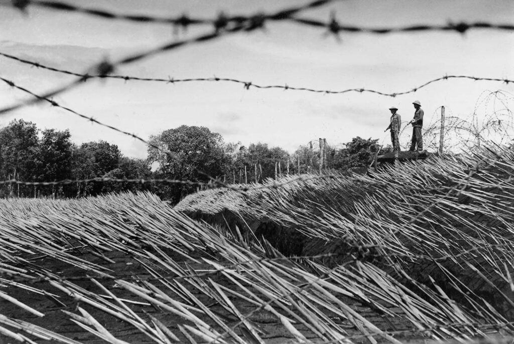 Guerrilheiros guardam um posto avançado na fronteira entre Vietnã e Camboja, protegido por estacas de bambu punji envenenadas. Afiadas e endurecidas pelo fogo, as estacas punji eram frequentemente escondidas onde os soldados inimigos as pisavam. Essas armadilhas eram destinadas a ferir, não a matar, porque soldados feridos atrasavam sua unidade e os transportes médicos revelavam sua posição. 1972. (Foto de Le Minh Truong).