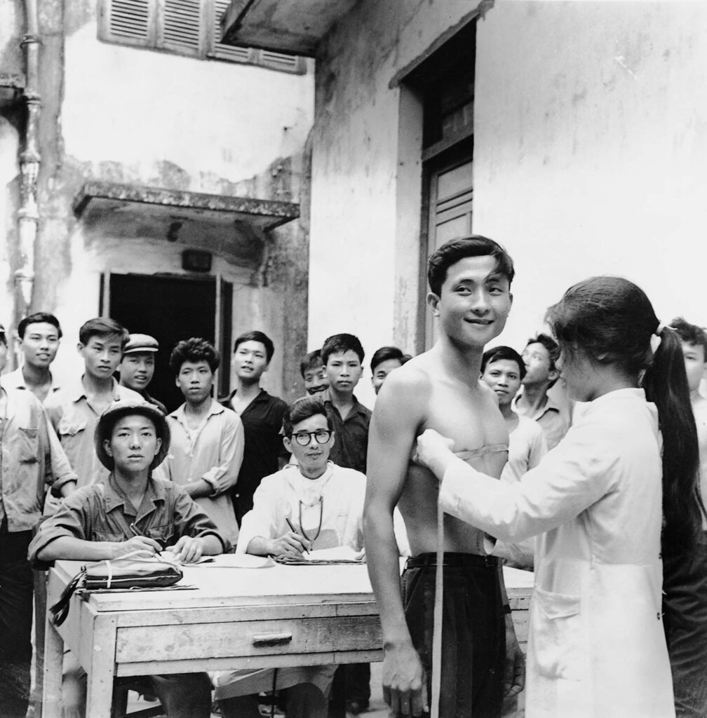 Novos recrutas passam por exames médicos em Haiphong. O sistema de voluntariado da Coreia do Norte foi transformado em um sistema obrigatório em 1973, quando todos os homens fisicamente aptos foram recrutados. De um corpo de cerca de 35.000 homens em 1950, o Exército Nacional Voluntário cresceu para mais de meio milhão de homens em meados da década de 70, uma força que os militares americanos reconheceram como uma das melhores do mundo. Julho de 1967. (Foto de Bao Hanh).