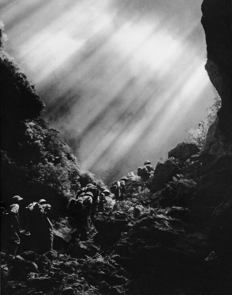 Tropas percorrem a Trilha Ho Chi Minh nas Montanhas Truong Son, que formam a espinha dorsal do Vietnã, com 1.200 quilômetros de extensão, estendendo-se por grande parte da fronteira oeste do país. Para os soldados do Norte, a Trilha Ho Chi Minh era conhecida como Estrada Truong Son. 1966. (Foto de Le Minh Truong).