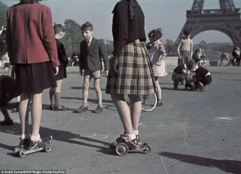 Meninas e meninos brincam no que parecem ser os primeiros precursores dos patins, tendo como pano de fundo a Torre Eiffel no Champ de Mars, no centro de Paris.