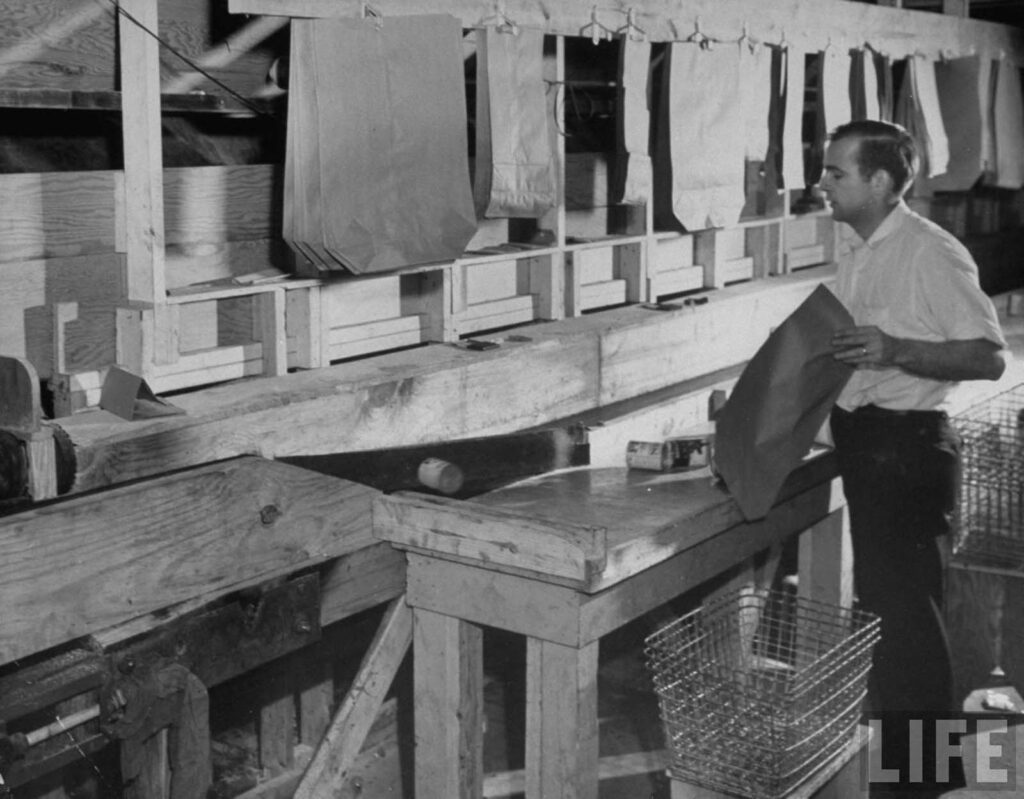 Funcionário da loja de alimentos automática Keedoozle ensacando o pedido de um cliente e colocando-o em uma esteira rolante.