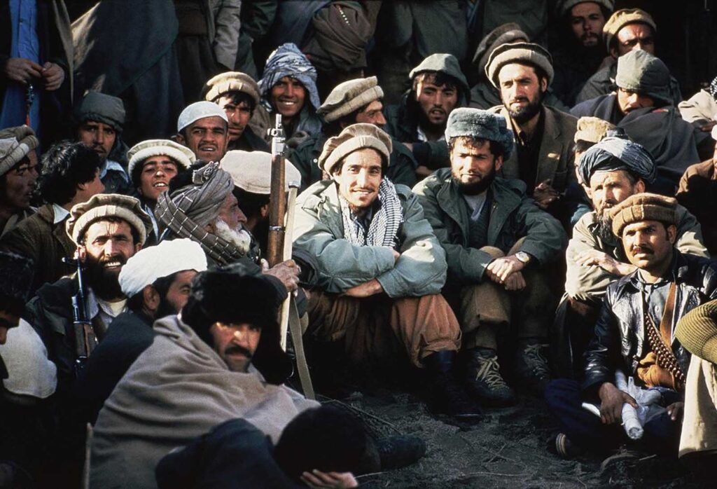 O líder guerrilheiro afegão, Ahmad Shah Massoud, ao centro, cercado por comandantes mujahideen em uma reunião dos rebeldes no Vale do Panchir, no nordeste do Afeganistão, em 1984. Massoud foi fundamental para grande parte da resistência antissoviética e, após a saída das tropas, lutou com outros para criar um novo governo. Em poucos anos, Massoud e suas forças lutaram contra o Talibã, e ele se tornou inimigo de Osama bin Laden. Em 9 de setembro de 2001, Massoud foi assassinado por dois agressores apoiados pela Al-Qaeda, poucos dias antes dos ataques de 11 de setembro contra os EUA.