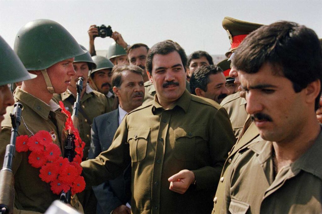 O presidente do Afeganistão, Mohammed Najibullah (centro), sorri ao encontrar soldados do Exército Vermelho em 19 de outubro de 1986, no centro de Cabul, durante um desfile. Najibullah, que se tornou presidente em 1986, foi enforcado em uma rua perto do complexo da ONU em Cabul em 27 de setembro de 1996, onde buscava refúgio desde abril de 1992, quando guerrilheiros mujahideen entraram na capital afegã.