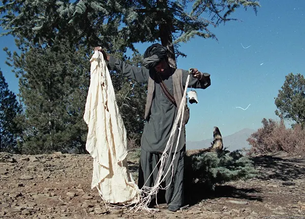Um combatente mujahedin segura os restos de uma bomba de paraquedas. O projeto permite que jatos de ataque terrestre lancem bombas em baixa altitude sem serem atingidos pela explosão.