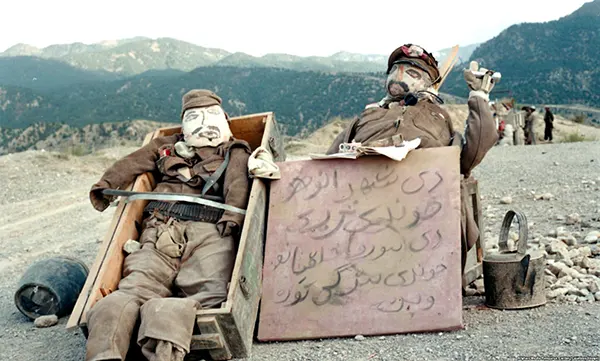 Bonecos de soldados soviéticos. A placa diz: "As irmãs de Shahr-e Naw" — um bairro de Cabul — "estão chorando, enquanto as irmãs dos comunistas estão embelezando os olhos".