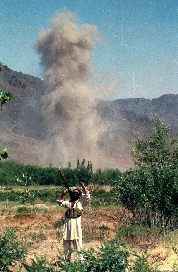 Um combatente mujahedin examina o céu após um ataque aéreo.