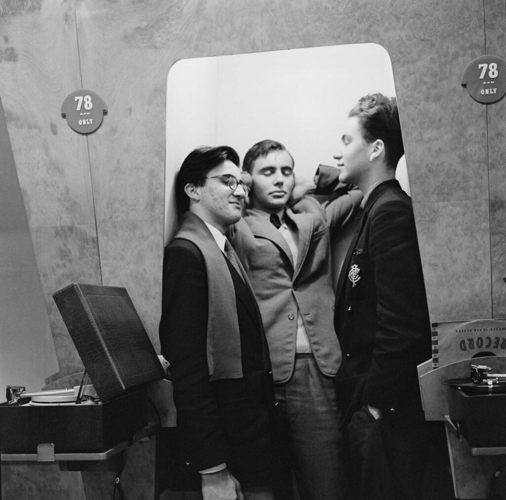 Um grupo de amigos curtindo música em uma cabine de audição. 1955.